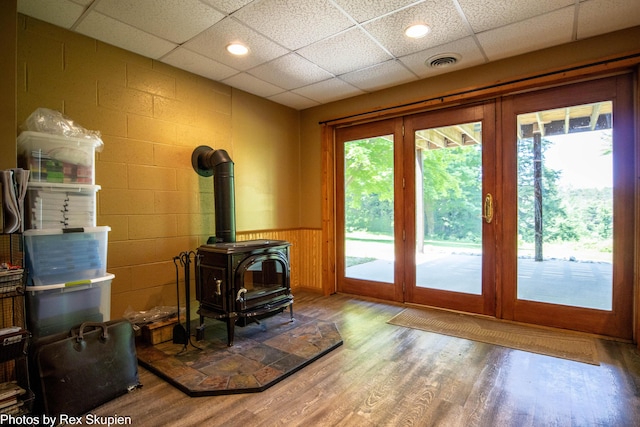 4585 W Arrowhead Dr, White Cloud, MI 49349 - unfurnished living room featuring plenty of natural light, a paneled ceiling, wood finished floors, a wood stove, and a wainscoted wall