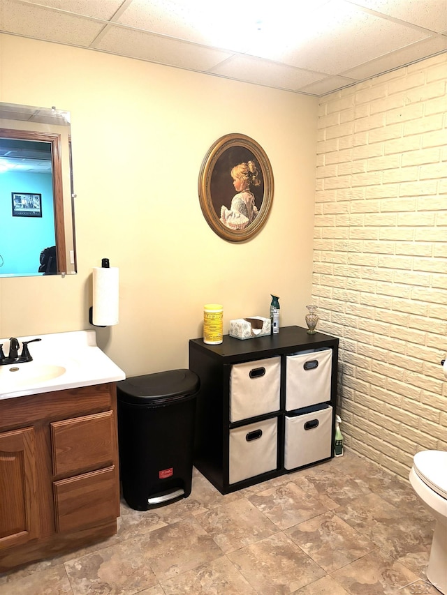 3004 Mackinaw Meadows Dr, Saginaw, MI 48603 - bathroom with brick wall, a drop ceiling, vanity, and stone finish floors