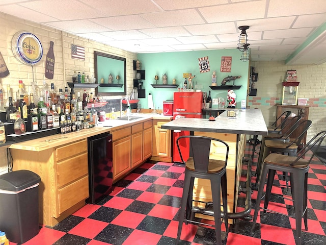 3004 Mackinaw Meadows Dr, Saginaw, MI 48603 - indoor wet bar featuring dark flooring, brick wall, and a paneled ceiling