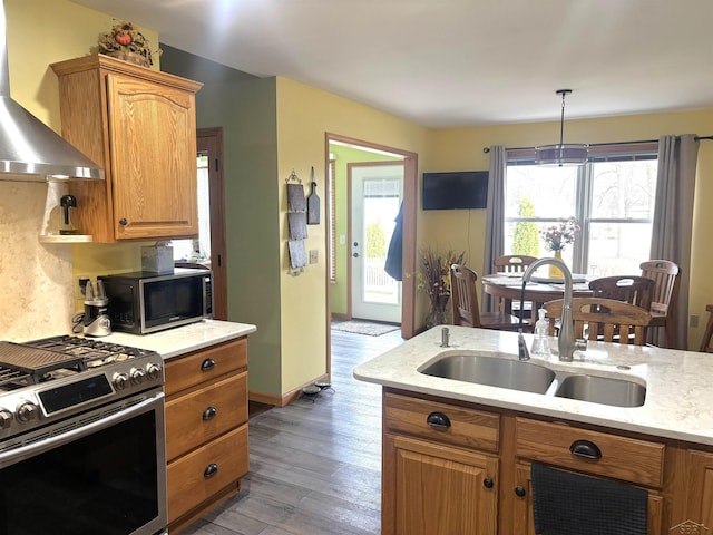 3004 Mackinaw Meadows Dr, Saginaw, MI 48603 - kitchen featuring wall chimney exhaust hood, gas stove, wood finished floors, brown cabinets, and light stone countertops