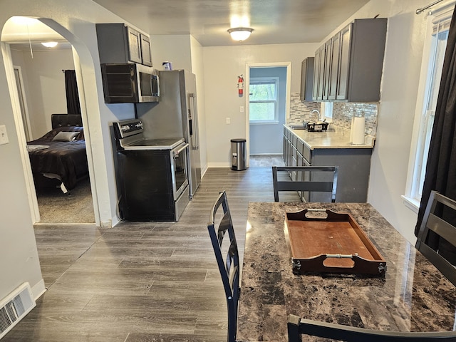 1406 Bixby Rd, Kalamazoo, MI 49048 - kitchen featuring stainless steel appliances, gray cabinetry, dark wood-style flooring, and arched walkways