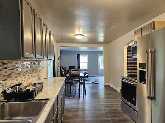 1406 Bixby Rd, Kalamazoo, MI 49048 - kitchen with stainless steel appliances, arched walkways, backsplash, dark wood-type flooring, and light stone counters
