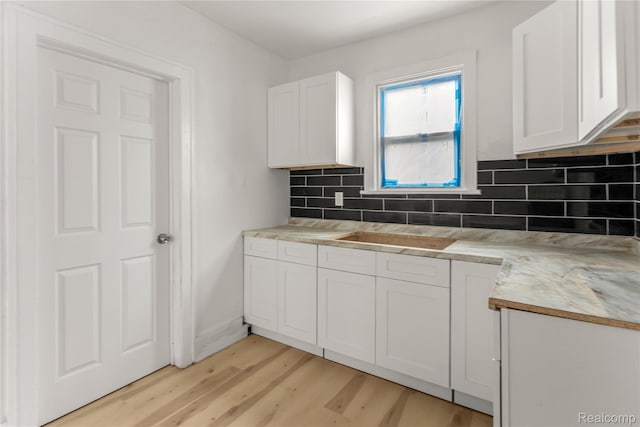 12719 Sussex St, Detroit, MI 48227 - kitchen with light wood-type flooring, white cabinets, decorative backsplash, and light countertops