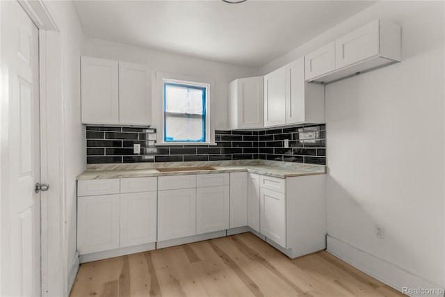 12719 Sussex St, Detroit, MI 48227 - kitchen with white cabinets, light wood-type flooring, decorative backsplash, and light countertops