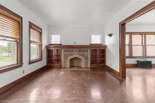 5527 Chalmers St, Detroit, MI 48213 - unfurnished living room with radiator, wood finished floors, a brick fireplace, and a textured ceiling