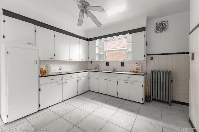 5527 Chalmers St, Detroit, MI 48213 - kitchen featuring radiator heating unit, ceiling fan, light marble finish floors, white cabinets, and tile walls