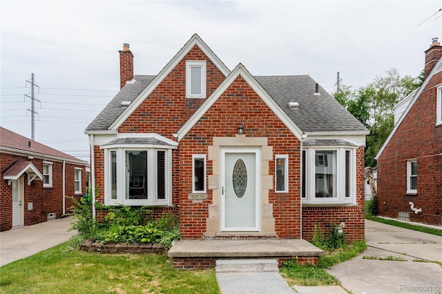 15648 Stricker Ave, Sterling Heights, MI 48021 - tudor home with brick siding, a chimney, and roof with shingles