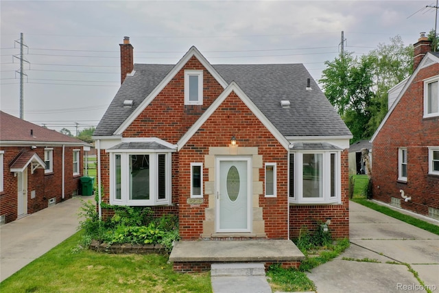 15648 Stricker Ave, Sterling Heights, MI 48021 - tudor home with brick siding, a shingled roof, and a chimney