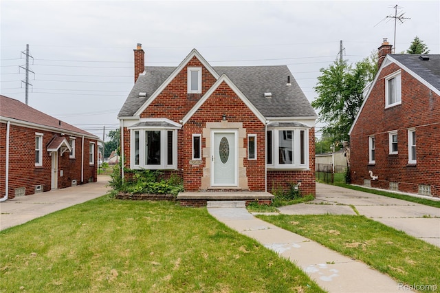15648 Stricker Ave, Sterling Heights, MI 48021 - tudor home featuring brick siding, roof with shingles, a front lawn, and a chimney