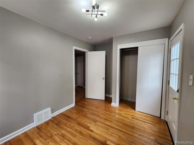248 W Longfellow Ave, Pontiac, MI 48340 - unfurnished bedroom with light wood-style flooring, a chandelier, and a closet