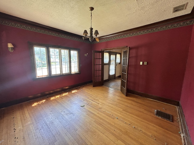 1407 Michigan Ave, Alma, MI 48801 - spare room with a textured ceiling, wood-type flooring, a chandelier, and french doors