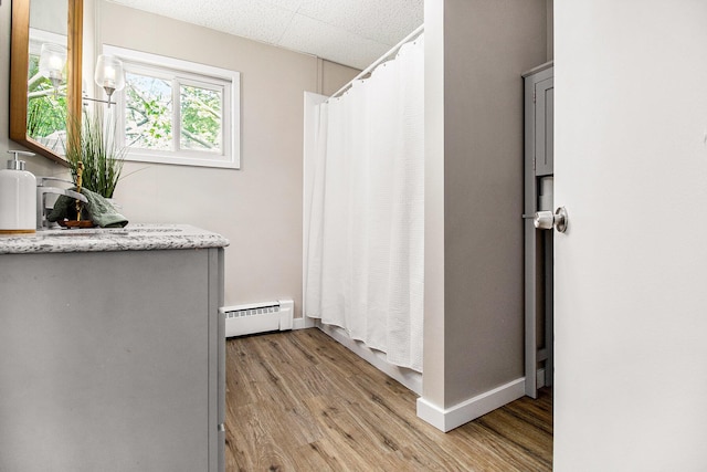 140 W Corey St, Bronson, MI 49028 - bathroom featuring a baseboard heating unit, wood finished floors, a shower with shower curtain, and vanity