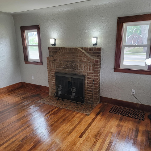 2356 SE Paris, Grand Rapids, MI 49507 - unfurnished living room featuring hardwood / wood-style flooring, plenty of natural light, a textured wall, and a brick fireplace