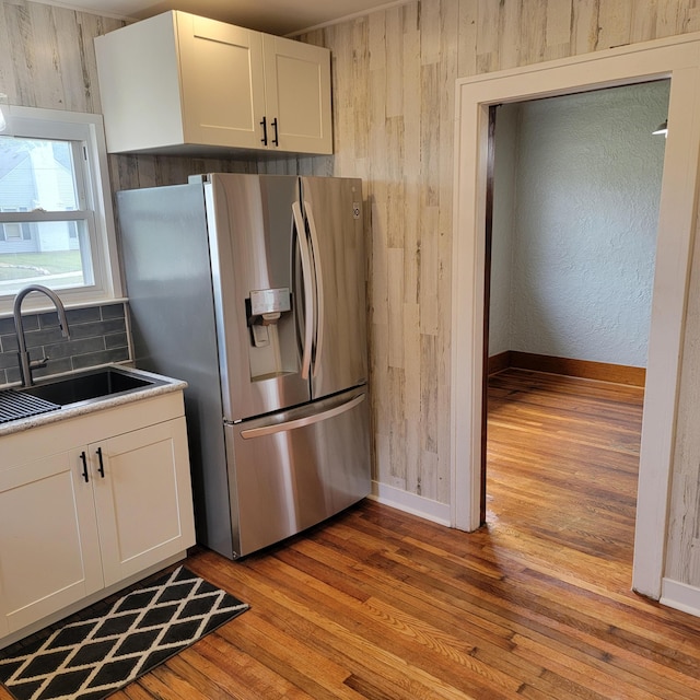 2356 SE Paris, Grand Rapids, MI 49507 - kitchen with stainless steel fridge, light wood-style floors, white cabinets, tasteful backsplash, and wood walls
