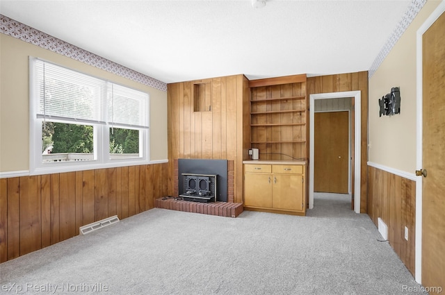 517 S Scott St, Adrian, MI 49221 - living area with wooden walls, a wood stove, light colored carpet, wainscoting, and built in shelves