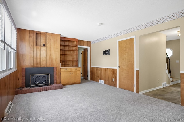 517 S Scott St, Adrian, MI 49221 - unfurnished living room with wood walls, plenty of natural light, stairs, a fireplace, and carpet