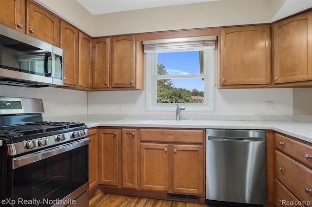 517 S Scott St, Adrian, MI 49221 - kitchen featuring appliances with stainless steel finishes, brown cabinetry, light countertops, and light wood-style floors