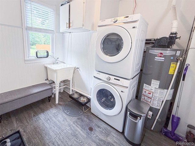 21110 Van Buren St, Southfield, MI 48033 - laundry room with water heater, stacked washer and clothes dryer, wood finished floors, and cabinet space