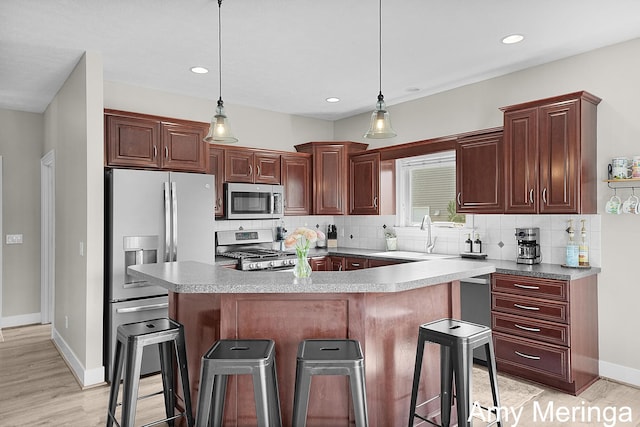 1824 Restoration Dr SW, Byron Center, MI 49315 - kitchen featuring appliances with stainless steel finishes, a breakfast bar, tasteful backsplash, a center island, and light wood-style flooring