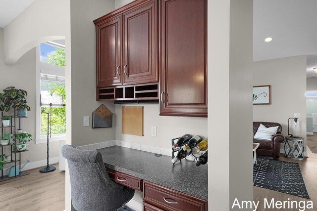1824 Restoration Dr SW, Byron Center, MI 49315 - home office with built in desk, plenty of natural light, arched walkways, light wood-style floors, and a towering ceiling
