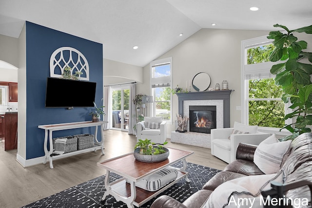 1824 Restoration Dr SW, Byron Center, MI 49315 - living area featuring light wood-style flooring, high vaulted ceiling, a glass covered fireplace, plenty of natural light, and recessed lighting