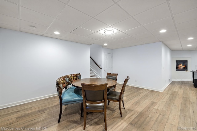1174 Lakeside Dr, Birmingham, MI 48009 - dining area featuring stairway, light wood finished floors, a glass covered fireplace, recessed lighting, and a paneled ceiling
