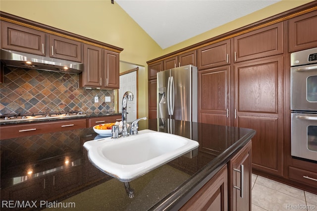 8922 Mcclements Rd, Brighton, MI 48114 - kitchen with appliances with stainless steel finishes, lofted ceiling, under cabinet range hood, backsplash, and dark stone counters