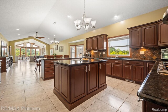 8922 Mcclements Rd, Brighton, MI 48114 - kitchen with a chandelier, vaulted ceiling, tasteful backsplash, a center island with sink, and hanging light fixtures