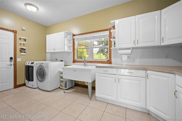 8922 Mcclements Rd, Brighton, MI 48114 - laundry area with cabinet space, washing machine and clothes dryer, a textured ceiling, and light tile patterned floors