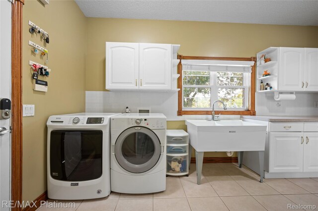8922 Mcclements Rd, Brighton, MI 48114 - washroom with cabinet space, washer and clothes dryer, and light tile patterned floors