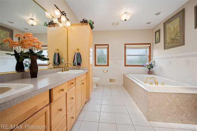 8922 Mcclements Rd, Brighton, MI 48114 - full bath with tile patterned floors, a bath, double vanity, tile walls, and a wainscoted wall