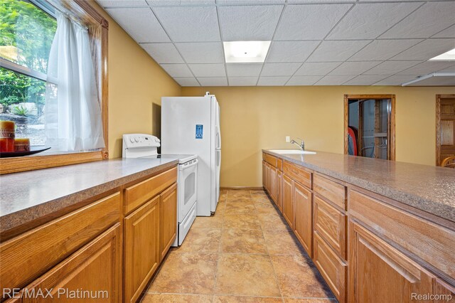 8922 Mcclements Rd, Brighton, MI 48114 - kitchen with white appliances, a paneled ceiling, and brown cabinets