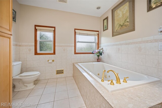 8922 Mcclements Rd, Brighton, MI 48114 - bathroom featuring healthy amount of natural light, a jetted tub, wainscoting, tile patterned flooring, and tile walls