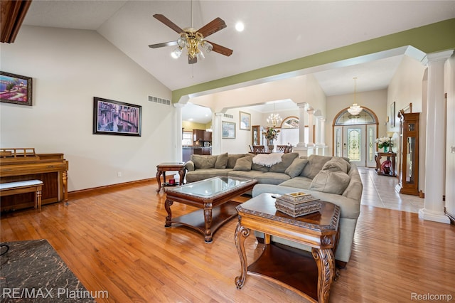 8922 Mcclements Rd, Brighton, MI 48114 - living area featuring ornate columns, high vaulted ceiling, ceiling fan, light wood-type flooring, and a chandelier