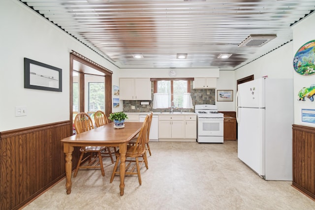 3750 River Rd, Manistee, MI 49660 - kitchen with white appliances, white cabinetry, light countertops, wainscoting, and decorative backsplash