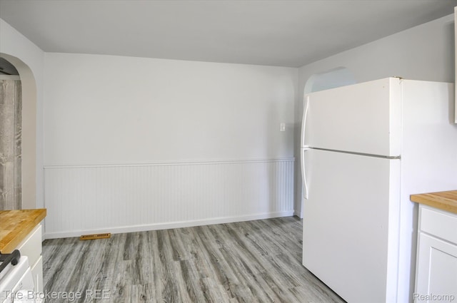 1372 S Packard Ave, Burton, MI 48509 - unfurnished dining area featuring light wood-type flooring, wainscoting, and arched walkways