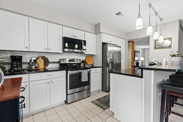 21112 Boulder Cir, Northville, MI 48167 - kitchen featuring appliances with stainless steel finishes, dark countertops, white cabinets, and decorative light fixtures