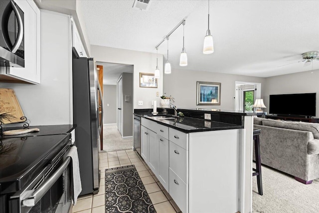 21112 Boulder Cir, Northville, MI 48167 - kitchen with appliances with stainless steel finishes, a breakfast bar area, open floor plan, white cabinetry, and a textured ceiling
