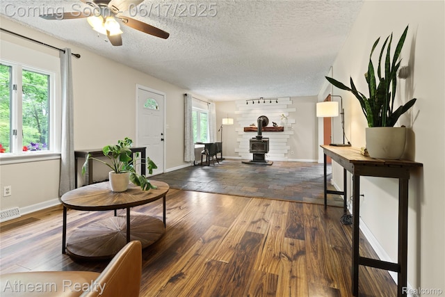 10129 Nimphie Rd, Fenton, MI 48430 - living room featuring hardwood / wood-style flooring, a ceiling fan, a textured ceiling, and a wood stove