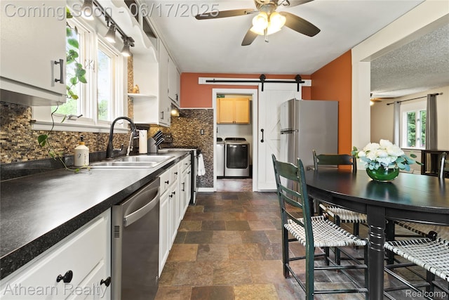 10129 Nimphie Rd, Fenton, MI 48430 - kitchen featuring ceiling fan, appliances with stainless steel finishes, a barn door, tasteful backsplash, and dark countertops