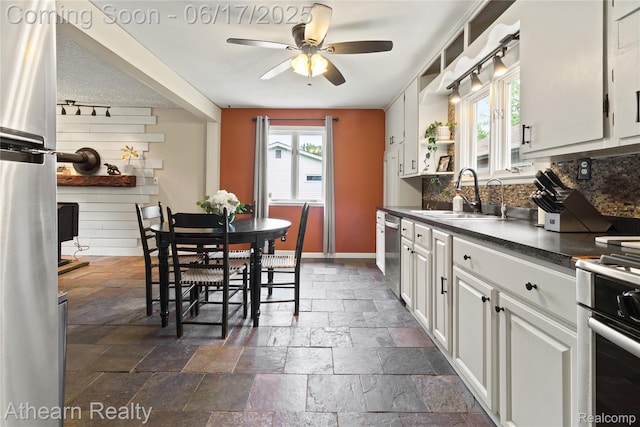 10129 Nimphie Rd, Fenton, MI 48430 - kitchen featuring stone tile floors, stainless steel appliances, dark countertops, ceiling fan, and white cabinetry