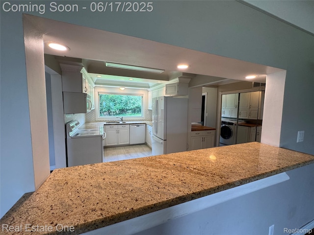 3340 Chickering Ln, Bloomfield Hills, MI 48302 - kitchen featuring washer / dryer, white appliances, decorative backsplash, white cabinetry, and light stone countertops