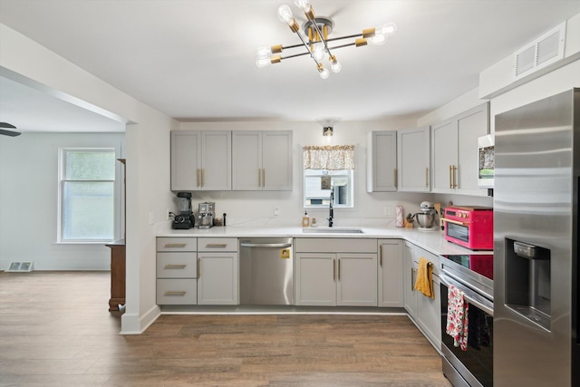 217 S Marshall Ave, Marshall, MI 49068 - kitchen with appliances with stainless steel finishes, gray cabinetry, a chandelier, and light countertops