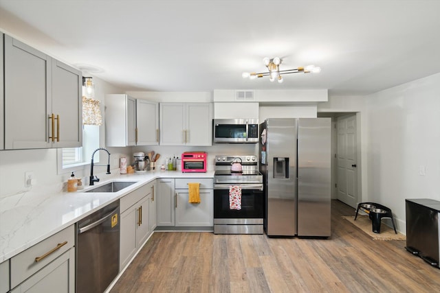 217 S Marshall Ave, Marshall, MI 49068 - kitchen with stainless steel appliances, light wood-type flooring, a chandelier, and gray cabinetry