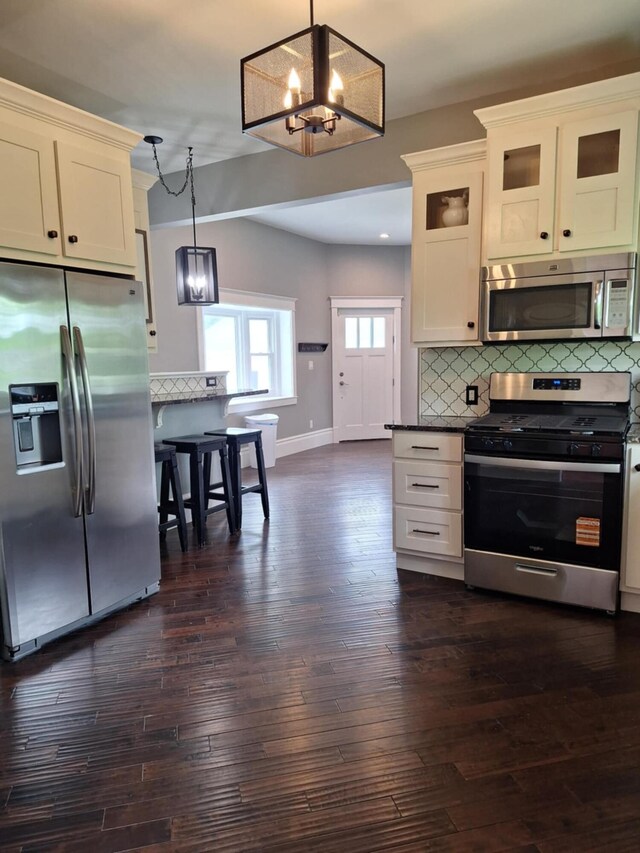 624 N Main St, Evart, MI 49631 - kitchen with appliances with stainless steel finishes, a chandelier, backsplash, glass insert cabinets, and dark wood-style flooring