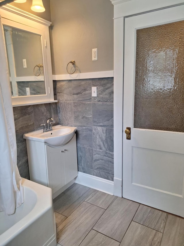 624 N Main St, Evart, MI 49631 - bathroom with tile walls, vanity, wood tiled floors, and a wainscoted wall