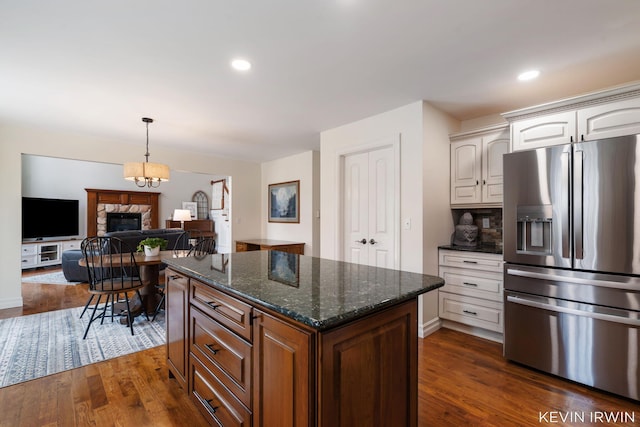19223 Fox Glove Cir, Big Rapids, MI 49307 - kitchen featuring stainless steel fridge with ice dispenser, a stone fireplace, dark wood finished floors, white cabinetry, and recessed lighting