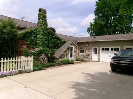 44 N Main St, Quincy, MI 49082 - view of front of house with concrete driveway, an attached garage, and stone siding