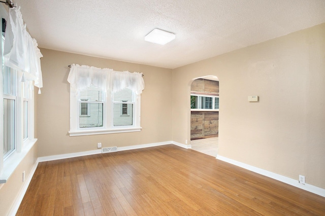 8464 E Michigan Ave, Galesburg, MI 49053 - empty room featuring wood-type flooring, arched walkways, and a textured ceiling
