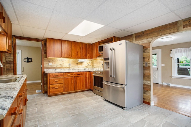 8464 E Michigan Ave, Galesburg, MI 49053 - kitchen with stainless steel appliances, a paneled ceiling, brown cabinets, tasteful backsplash, and arched walkways